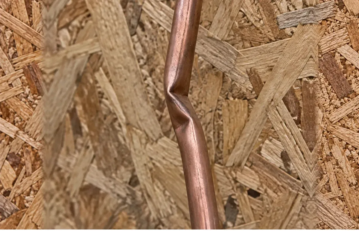 Kinked copper line set against wall sheathing